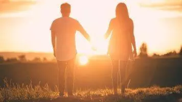 Ein Paar, das im Sonnenuntergang Händchen hält. Die beiden haben sich den Rosenthal-Effekt in ihrer Beziehung zu nutze gemacht.