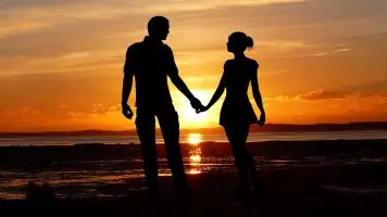 Ein Paar am Strand, das Händchen hält und den Urlaub ohne Streit genießt